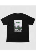 A black short-sleeve crewneck t-shirt featuring a graphic print on the front with a green UFO flying over purple trees and the text 'I WANT TO BELIEVE' Xfiles X-Files